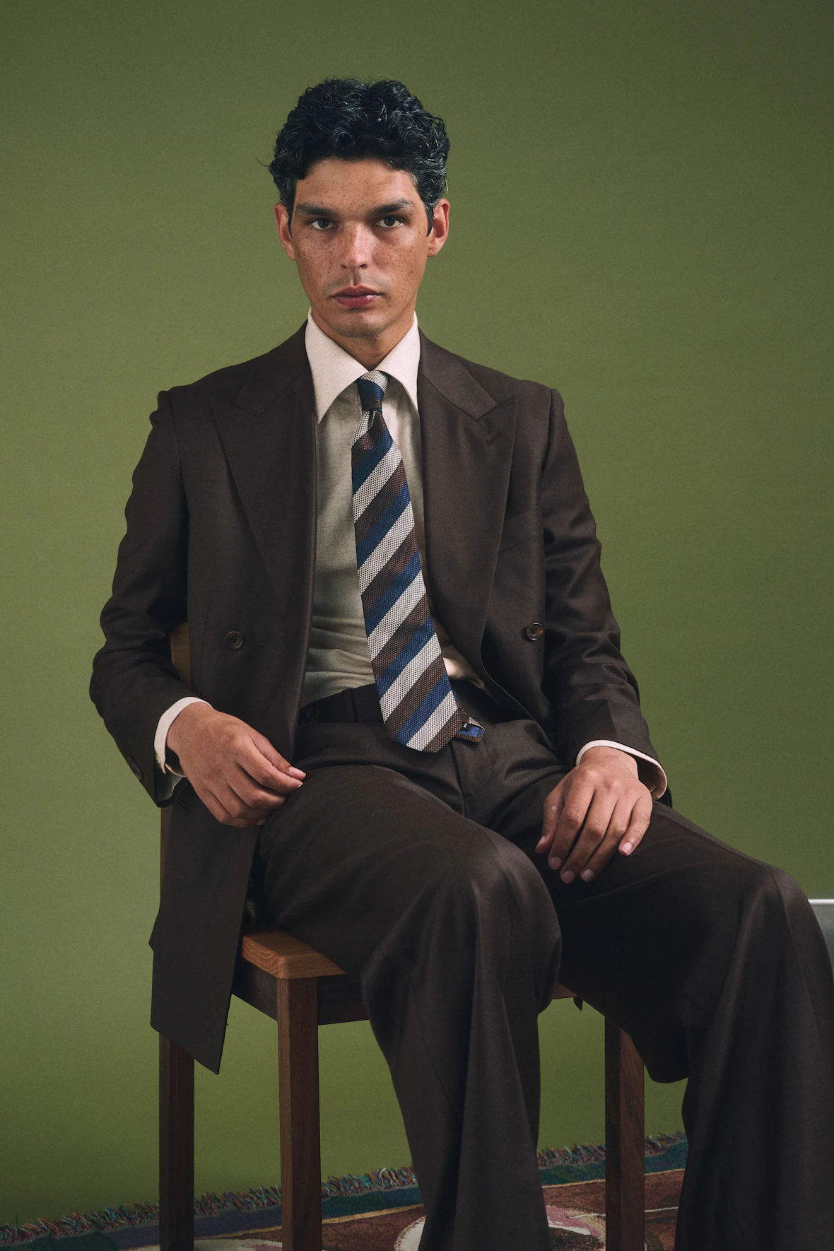 The Piemonte Loro Piana brown wool suit worn seated with a striped tie