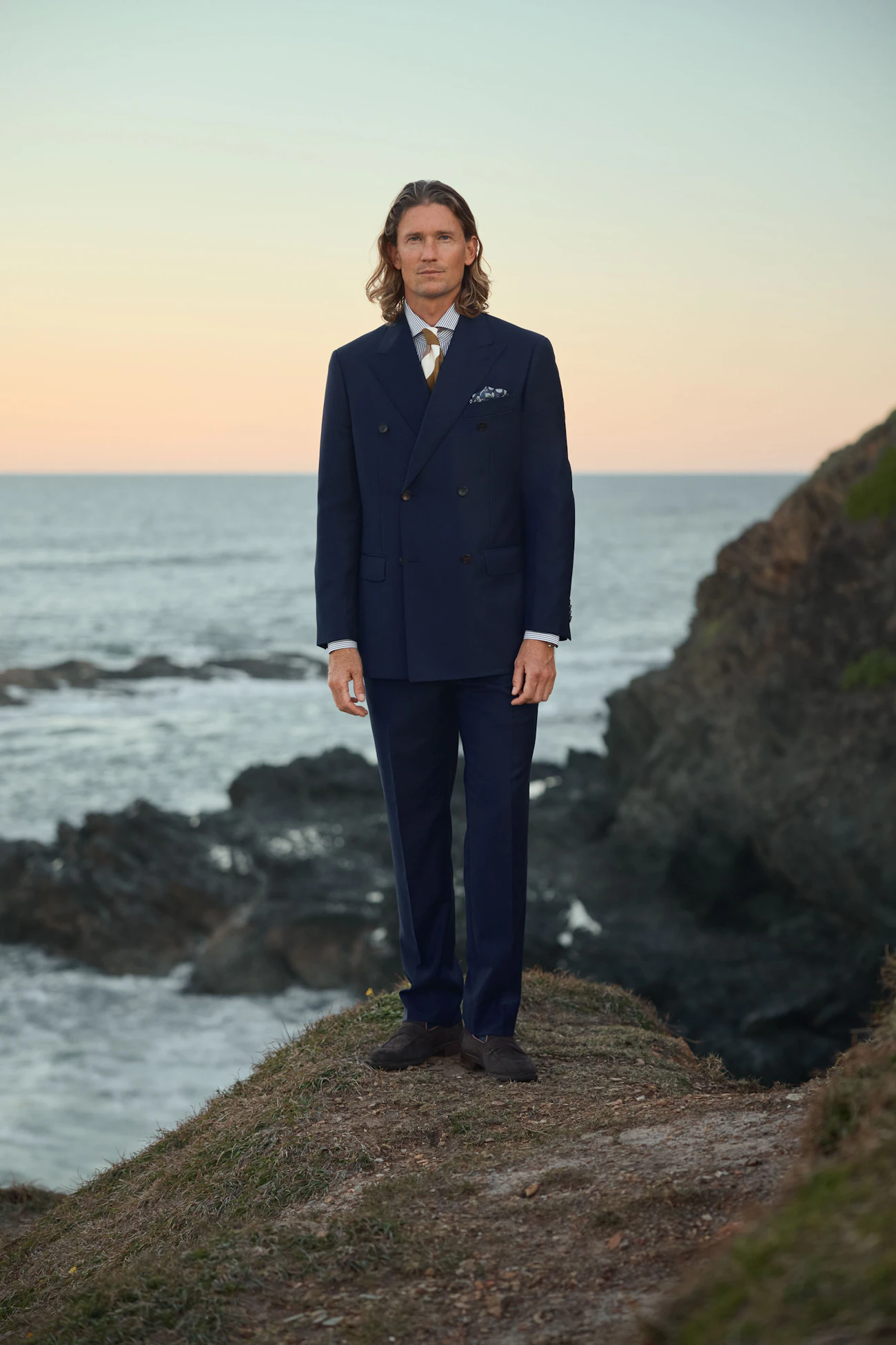 Full-length view of the Esperence navy wool suit on a headland at dusk
